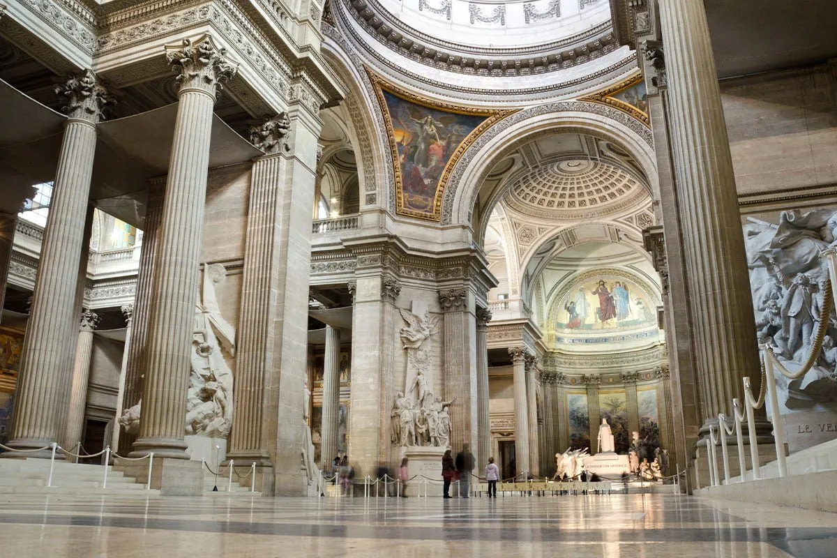 Wnętrze Panteonu w Paryżu, z imponującymi kolumnami, kopułą i malowidłami.