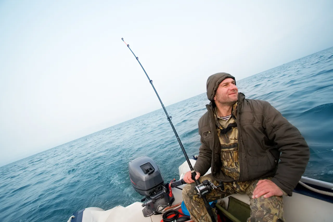 Mężczyzna na łodzi z wędką, zastanawia się, na co łowić ryby w Chorwacji.