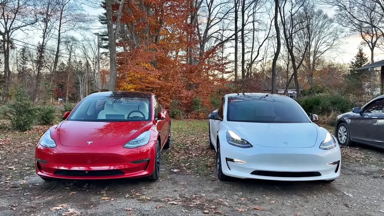 Dwie Tesle, czerwona i biała, stoją obok siebie na tle jesiennego lasu. Idealne do podr&oacute;ży do 100 km.