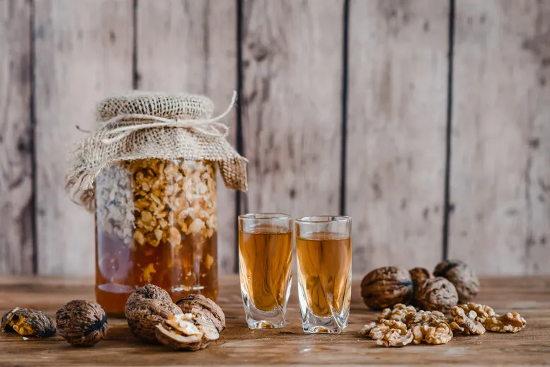 składniki na nalewkę z orzecha włoskiego, słój z orzechami i alkoholem