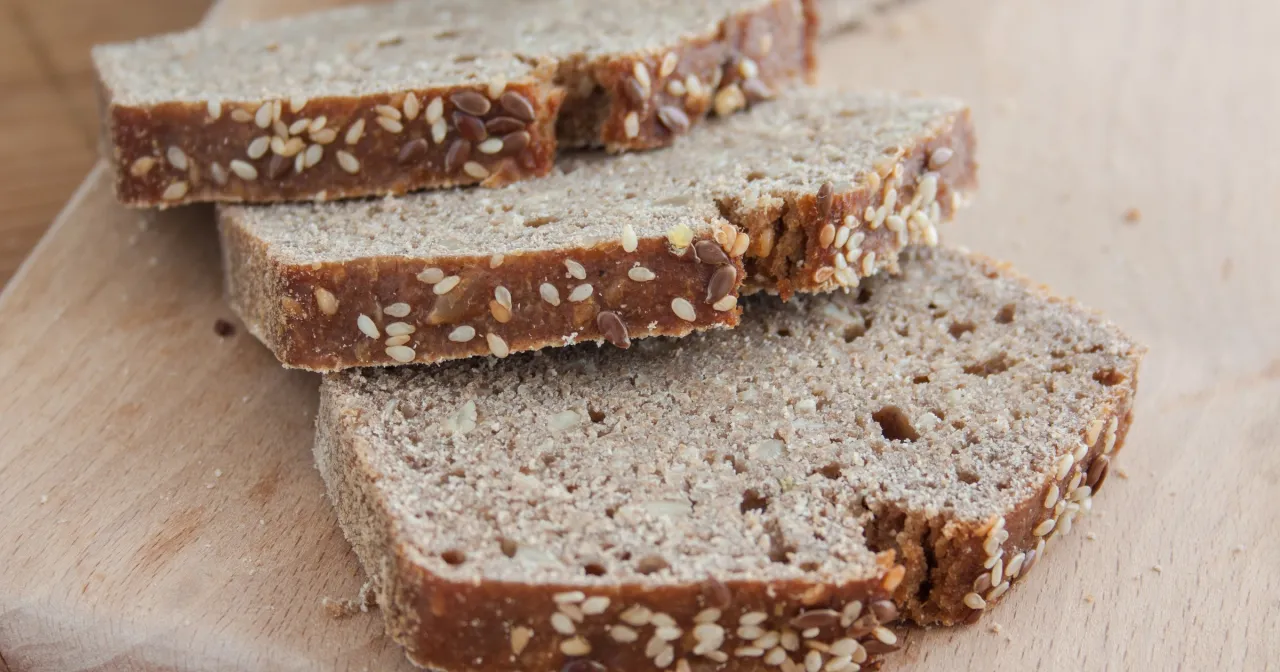 Trzy kromki chleba orkiszowego z ziarnami sezamu i siemienia lnianego. Zastanawiasz się, ile kalorii ma kromka chleba orkiszowego?