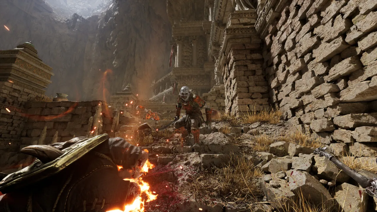 Wojownik z gry Dark Messiah of Might & Magic walczy z potworem na kamiennych schodach, otoczony ruinami i płomieniami.