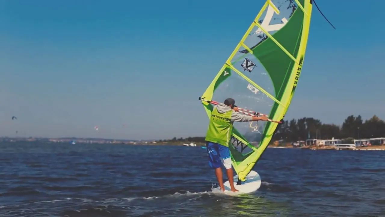 Instruktor windsurfingu pomaga uczniowi na wodzie