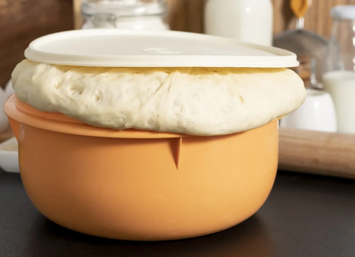 Wyrośnięte ciasto drożdżowe na suchych drożdżach w pomarańczowej misce. Idealne do wypiek&oacute;w, gdy szukasz sprawdzonego przepisu.