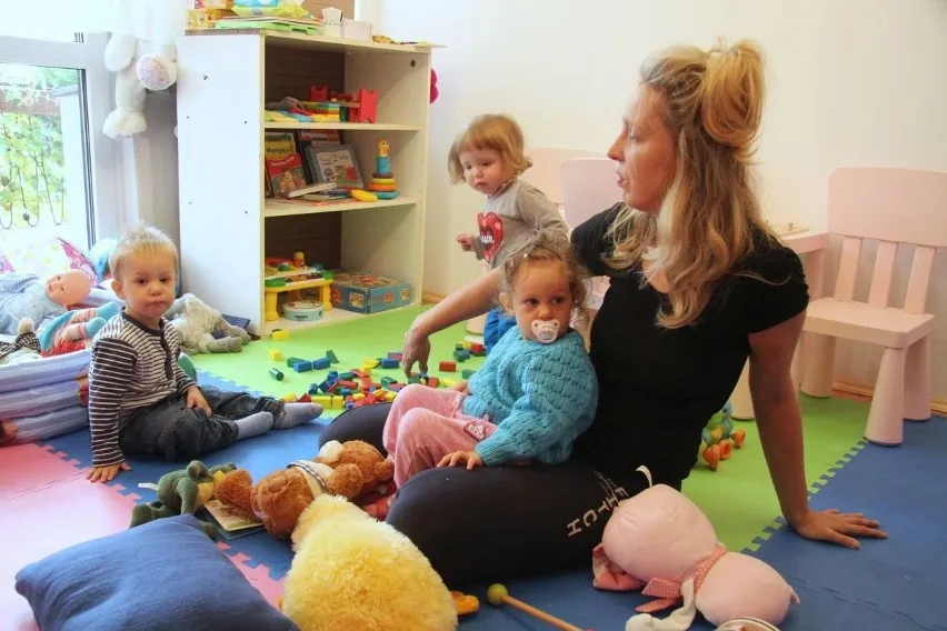 Szczęśliwe dziecko w żłobku bawi się z opiekunką