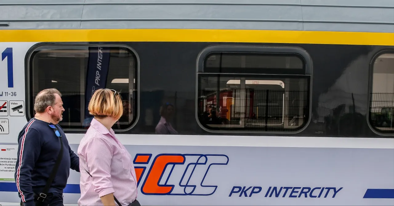 Para, stojąca obok pociągu PKP Intercity, zastanawia się, ile wagon&oacute;w ma intercity.