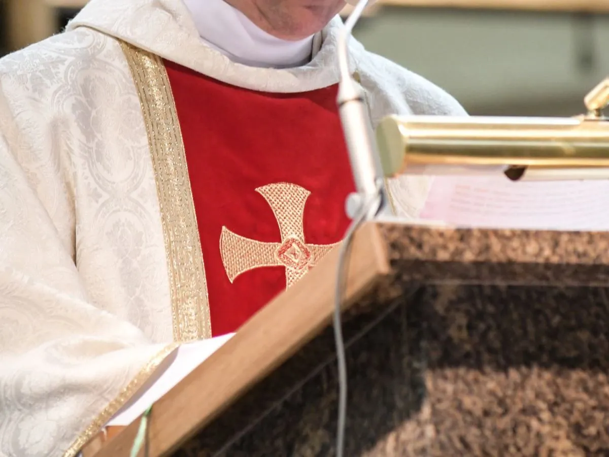 Ksiądz w uroczystej szacie z krzyżem, przygotowujący się do ostatniej mszy, kiedy ksiądz idzie na emeryturę.