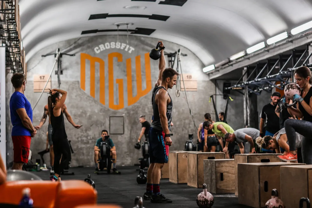 Intensywny trening w CrossFit Warszawa. Ludzie ćwiczą z kettlebellami i na wioślarzach. Gdzie jest najlepszy CrossFit w Warszawie? Tutaj!