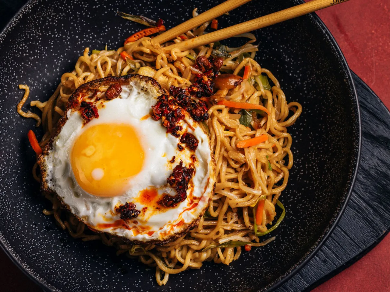 Gebratene Nudeln in einer Pfanne mit frischem Gem&uuml;se und Spiegelei