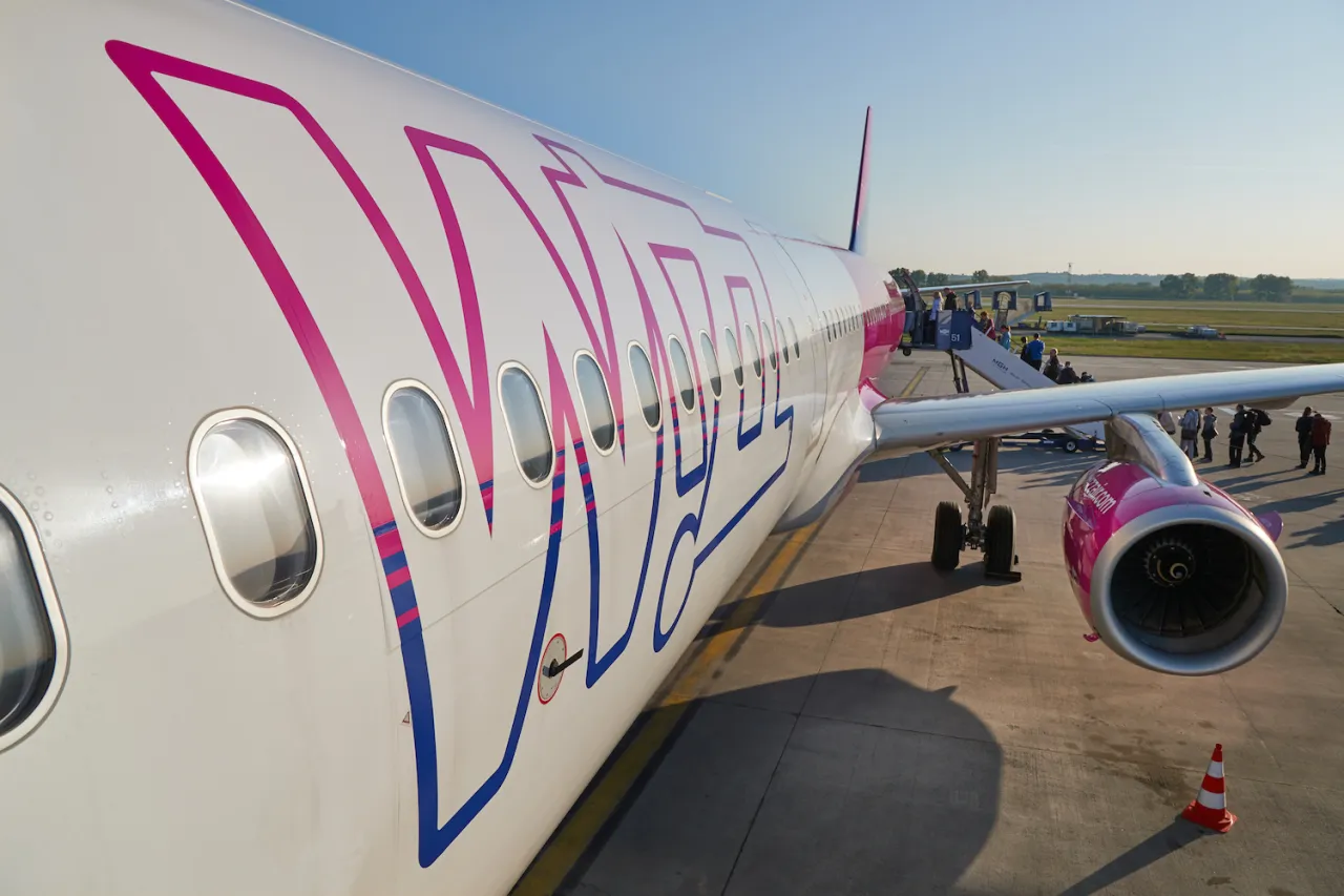 Samolot Wizzair, tanie linie lotnicze, gotowy do startu. Pasażerowie wsiadają po schodkach.