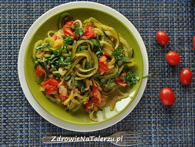 apetyczne spaghetti z cukinią i pomidorami na talerzu