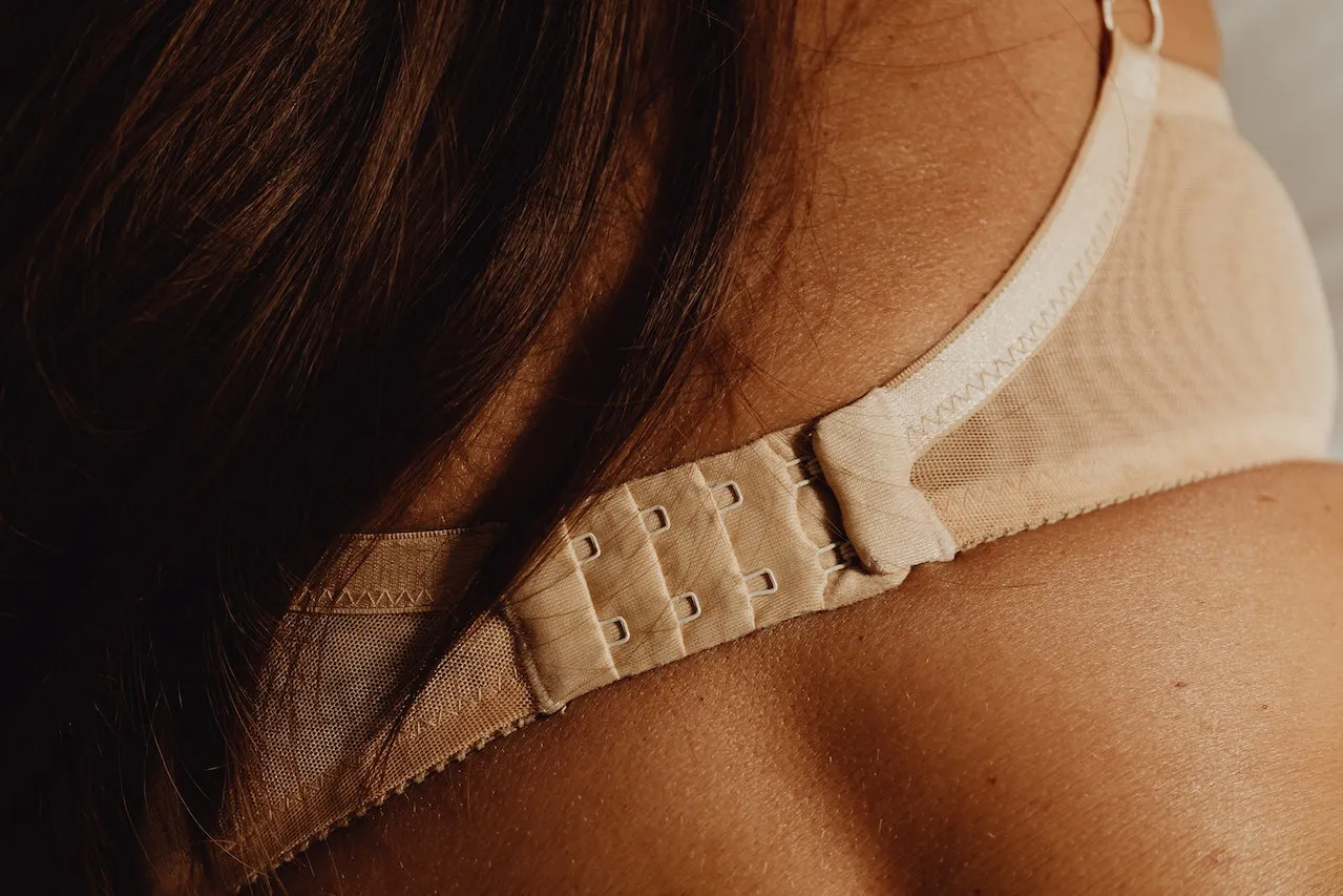 Zbliżenie na plecy kobiety, gdzie widać zapięcie stanika. Delikatna fiszbina w staniku zapewnia komfort i wsparcie.