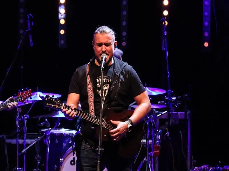 muzyk grający na gitarze i śpiewający do mikrofonu na scenie