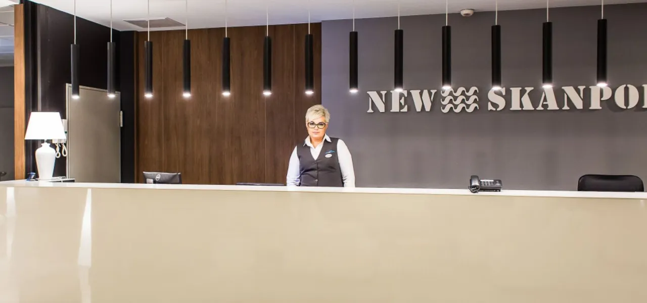 recepcja hotelowa, cennik basenu, osoba rozmawiająca z recepcjonistą