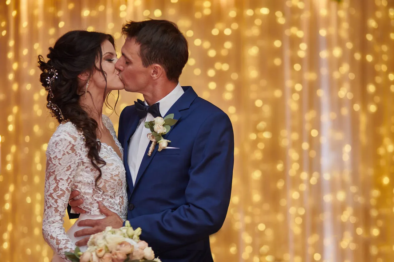 Para dowiedzieć się, ile kosztuje fotograf i kamerzysta na wesele, warto zobaczyć ten romantyczny pocałunek pary młodej na tle złotych świateł.