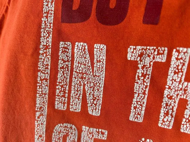 zniszczona koszulka z popękanym nadrukiem po praniu