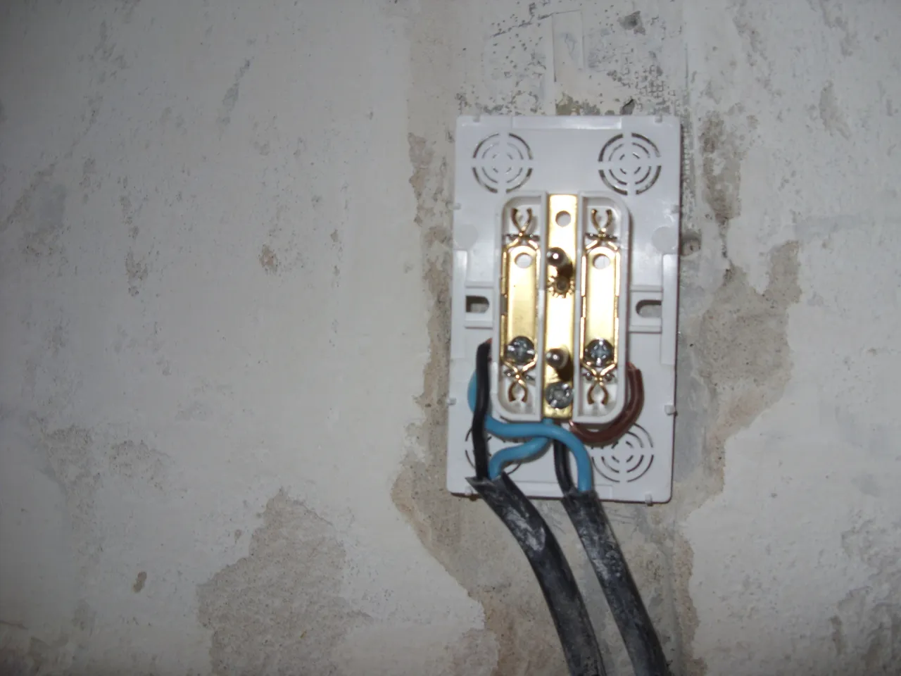 Widoczne przyłącze elektryczne z przewodami. Widać potencjalne małe napięcie na przewodzie neutralnym, co może być niebezpieczne.