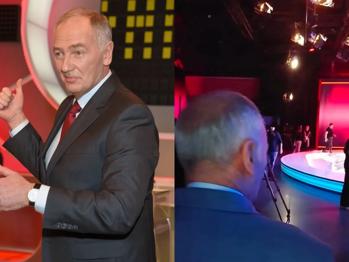 Mężczyzna w garniturze daje kciuk w g&oacute;rę, jakby chciał być zdrowy jak Familiada. W tle widać studio telewizyjne.