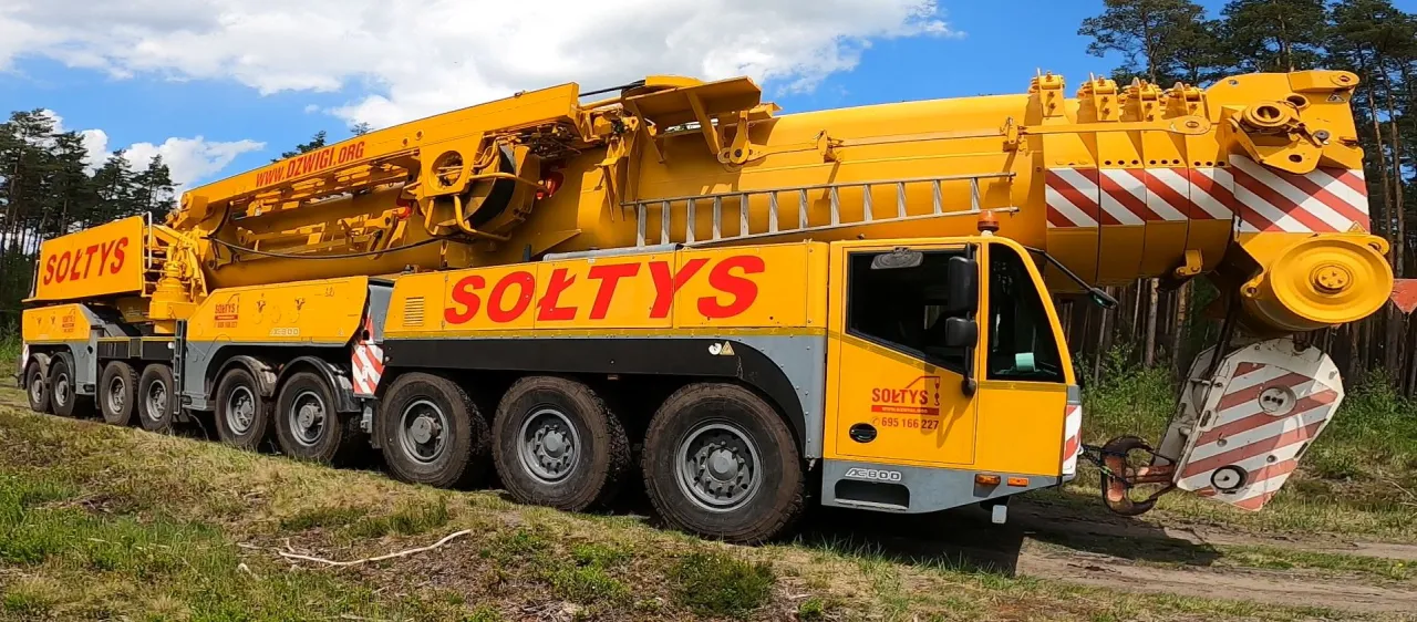 Ż&oacute;łty dźwig budowlany Soltys AC800, gotowy do pracy. Zastanawiasz się, ile kosztuje dźwig budowlany? Ten potężny sprzęt to inwestycja.
