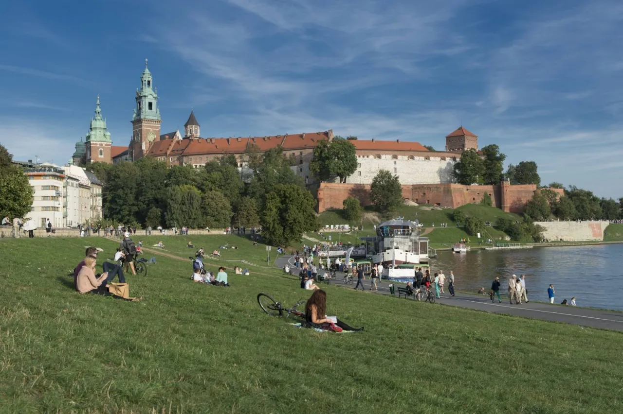 Rodzina spacerująca po Bulwarach Wiślanych w Krakowie z widokiem na Wawel