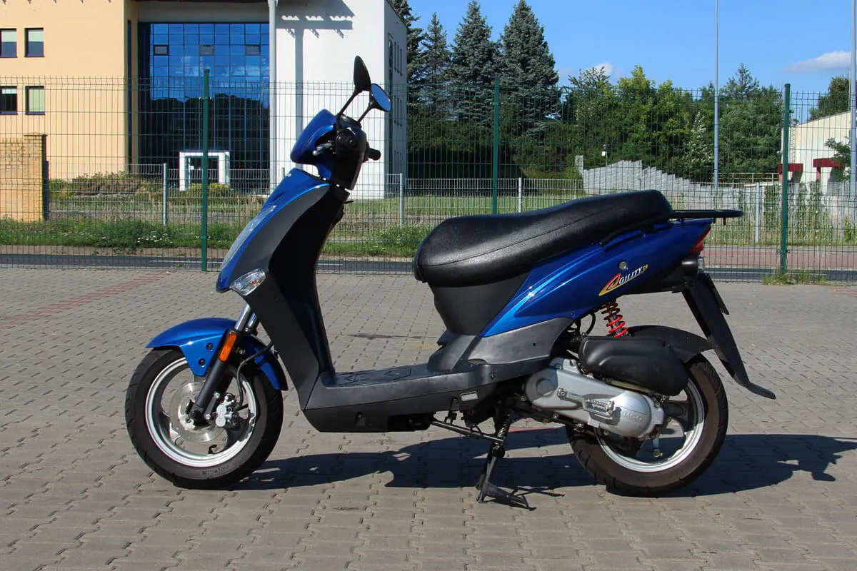 Błękitny skuter stoi na chodniku. Zastanawiasz się, jakie prawo jazdy na skuter jest potrzebne?