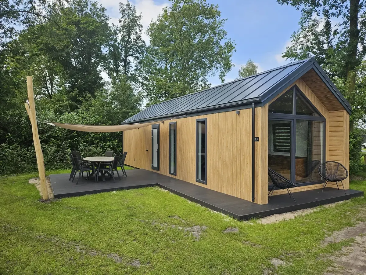 Nowoczesny domek letniskowy z tarasem i meblami ogrodowymi. Zastanawiasz się, czy potrzebne jest zgłoszenie czy pozwolenie na budowę?