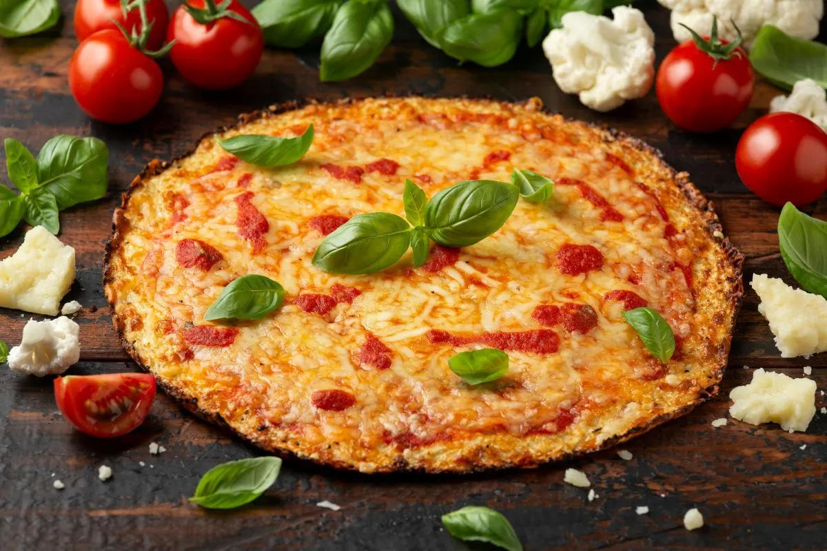 Pizza z kalafiora, posypana serem i bazylią. Czy kalafior jest dietetyczny? Tak, ta pizza to dowód!