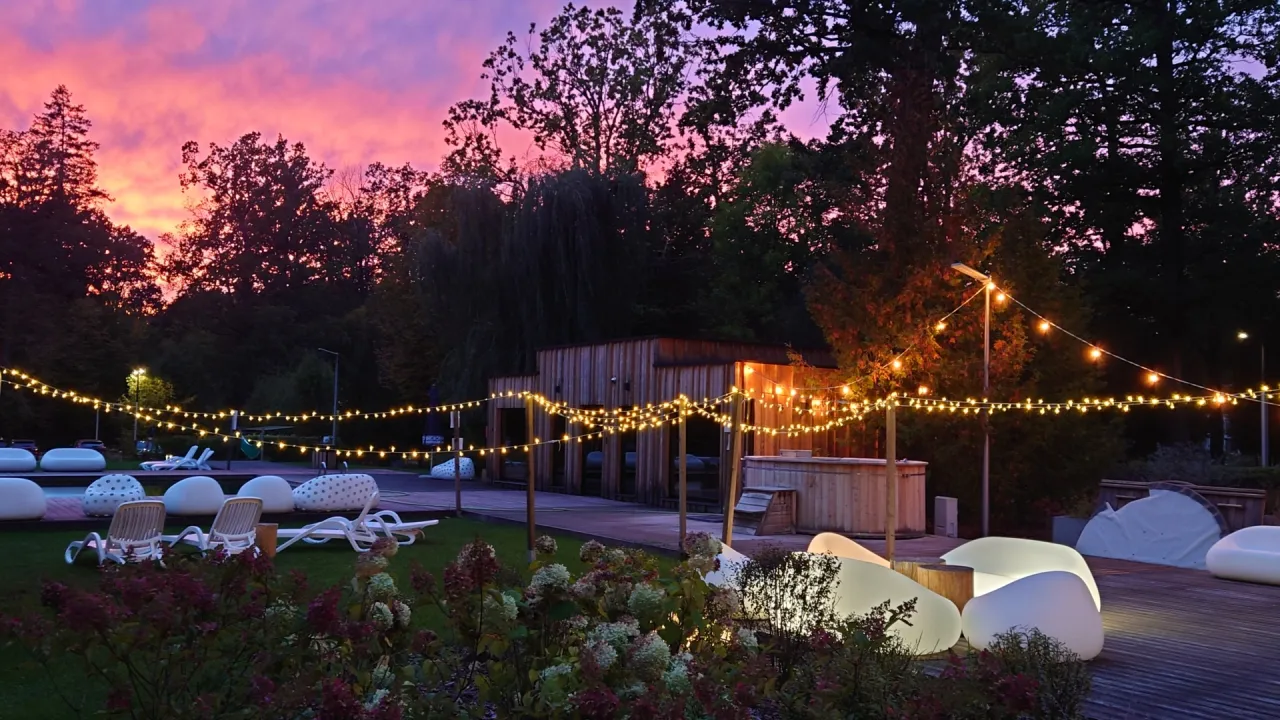 Wieczorny relaks w spa Białystok i okolice. Girlandy światełek, jacuzzi i wygodne leżaki pod fioletowym niebem.