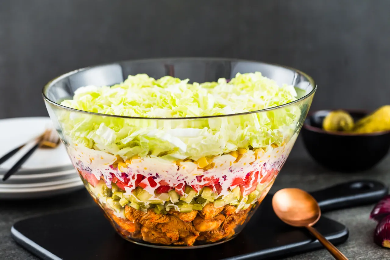 Warstwowa sałatka gyros w szklanej misie: kurczak, ogórek, pomidor, kukurydza, jajko, sos i sałata pekińska. Idealne co do sałatki gyros.