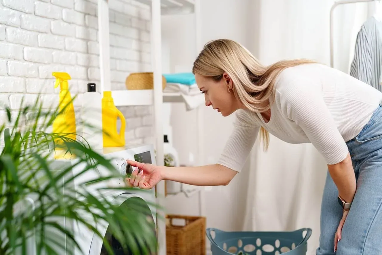 Kobieta ustawia pralkę, by dowiedzieć się, jak prać kurtkę jeansową z futerkiem.