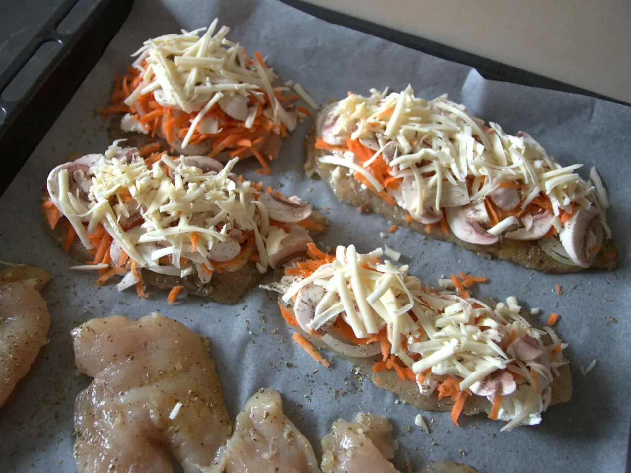 Piersi z kurczaka z tartym serem, marchewką i pieczarkami, gotowe na pyszny obiad.
