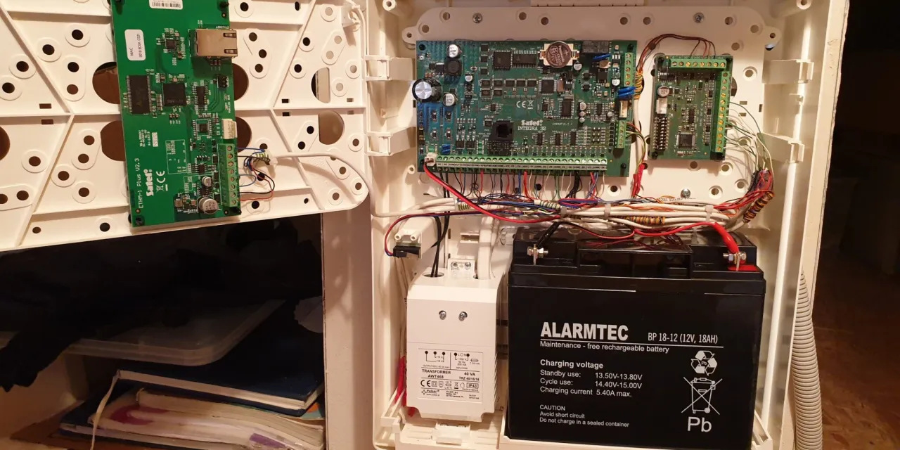 Wnętrze centrali alarmowej: płytki drukowane, transformator i akumulator. Schematyczne przedstawienie, jak podłączyć alarm w domu.