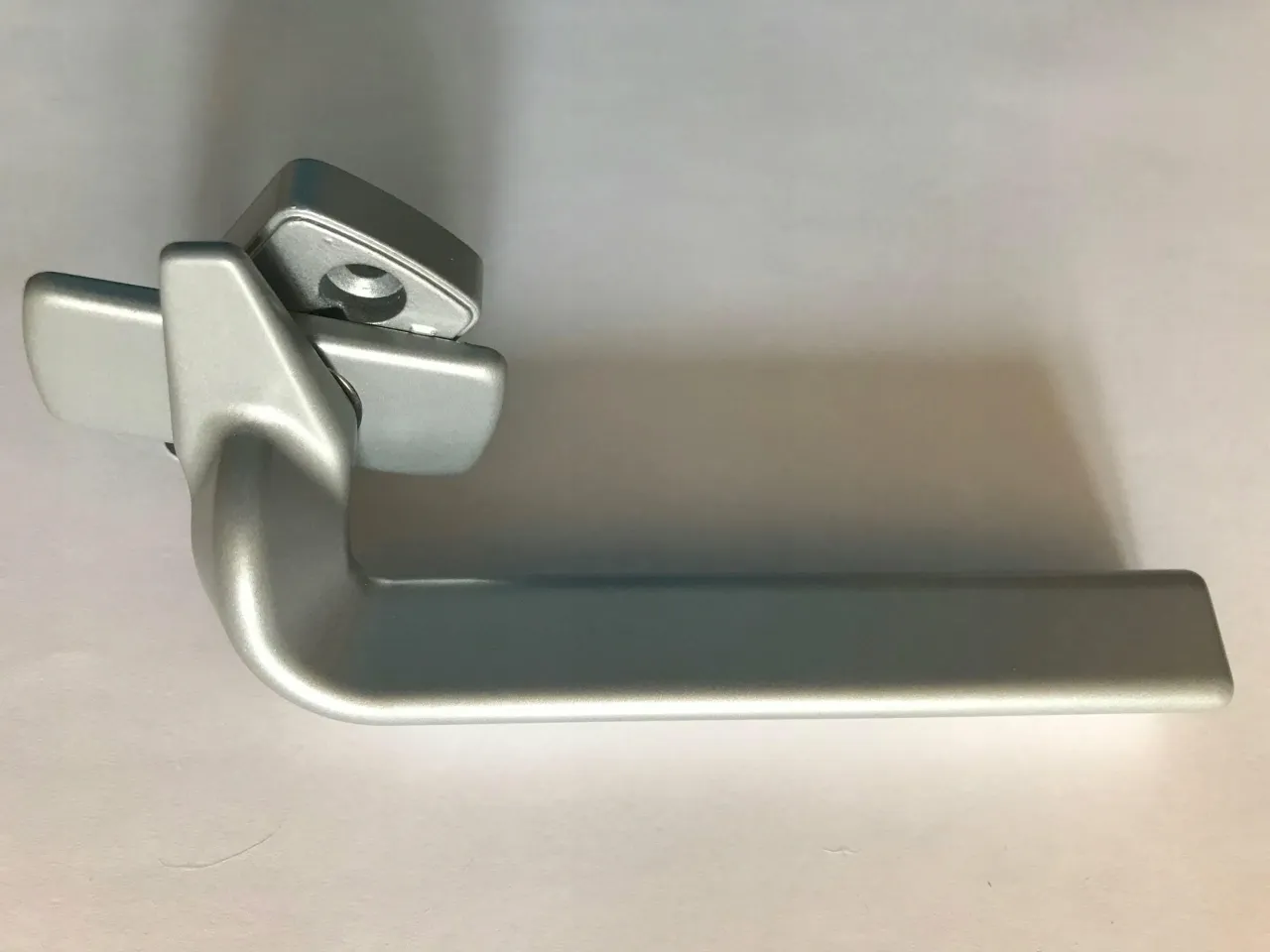 Srebrna klamka do okien drewnianych, z mechanizmem blokującym, idealna do nowoczesnych wnętrz.