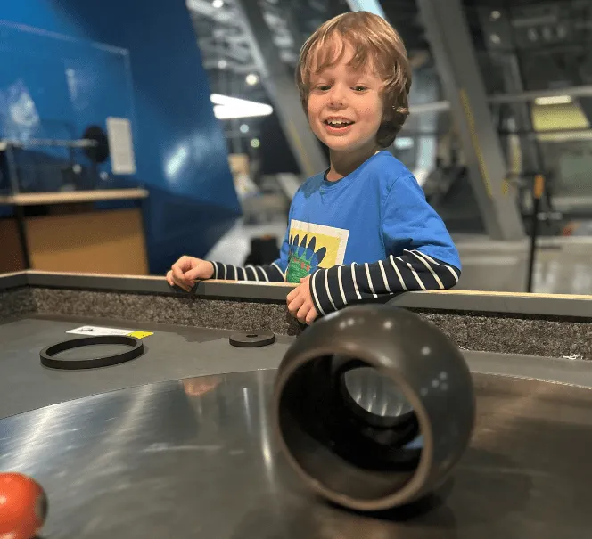 dziecko w wieku szkolnym w centrum nauki patrzące na eksponat