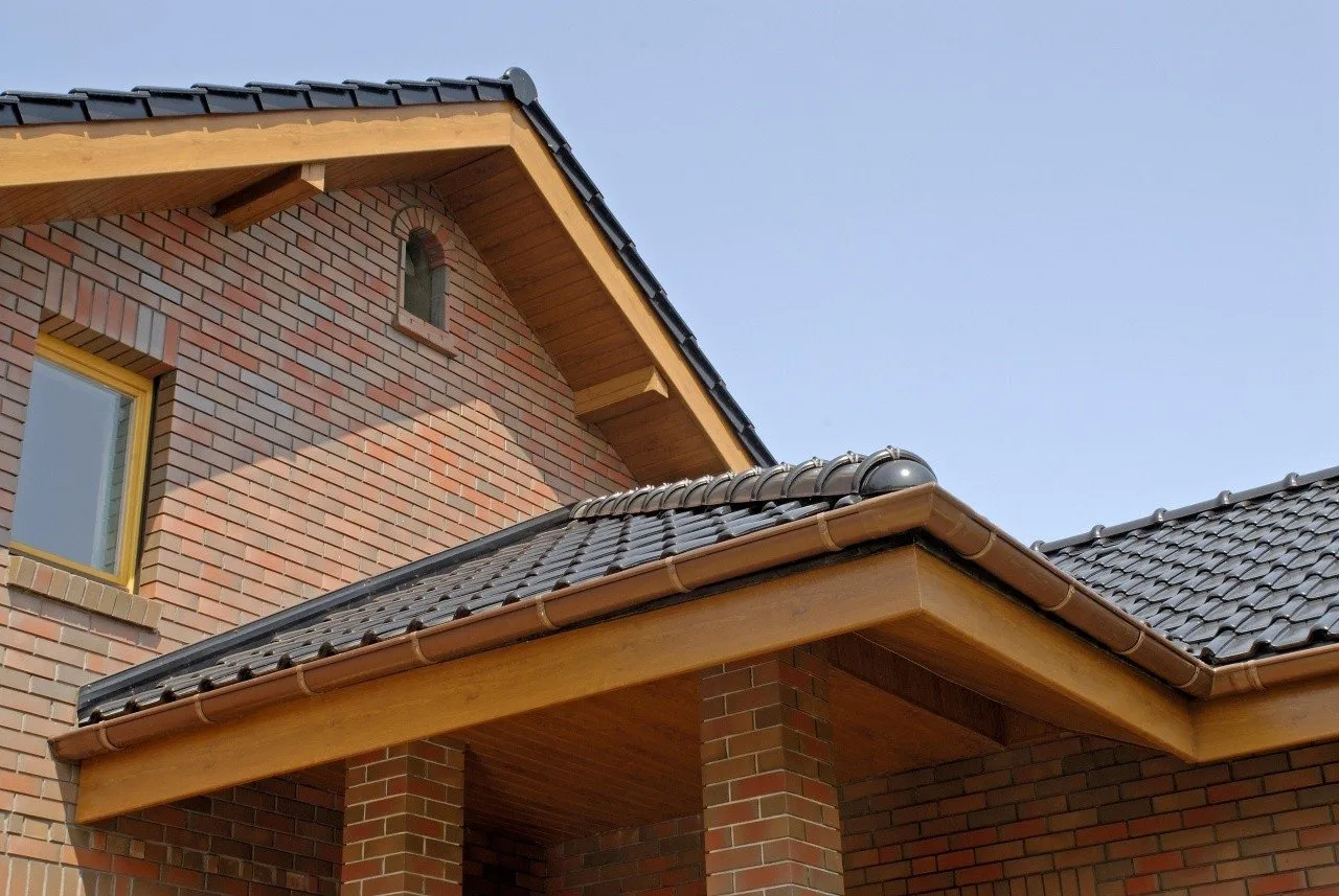 Nowy dach z dachówką i drewnianą blachą na desce czołowej.