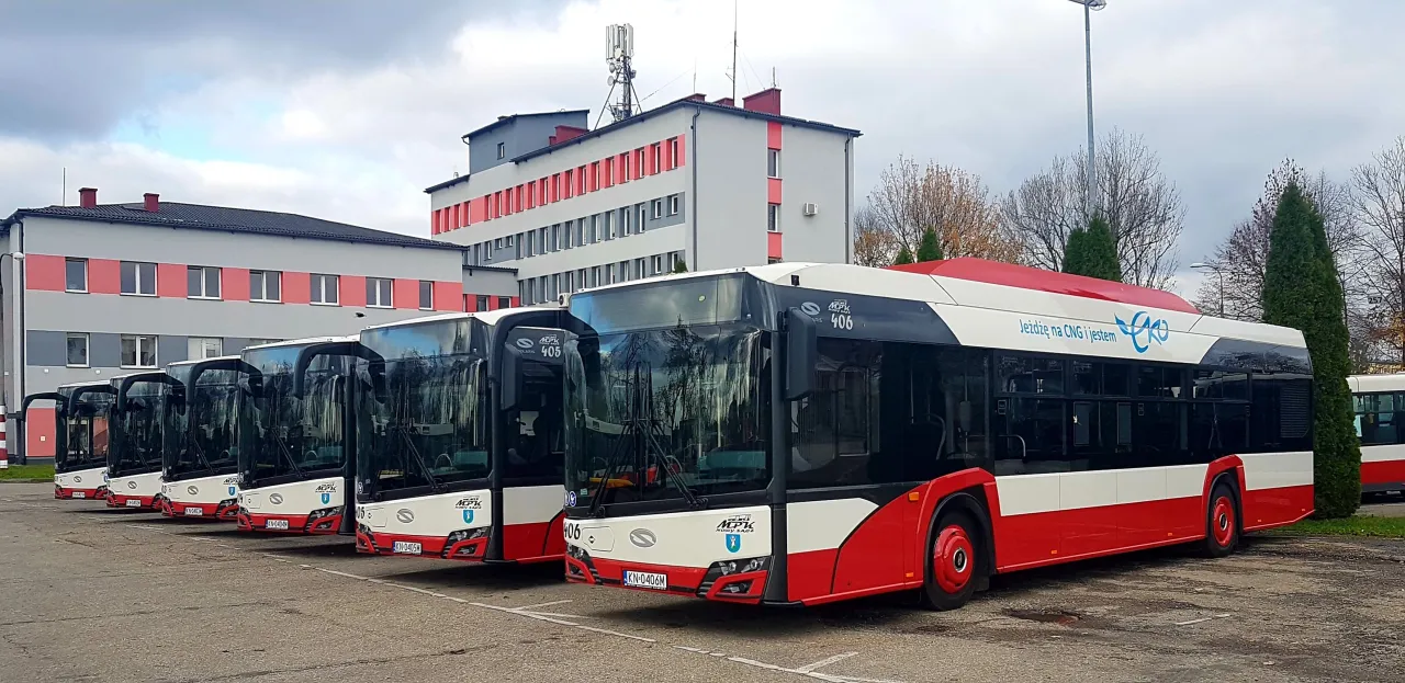 Rząd nowoczesnych autobusów MPK Nowy Sącz zaparkowany przed budynkiem.