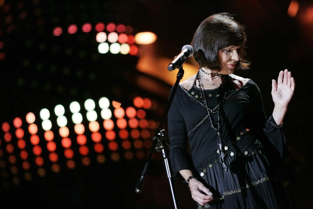 Kto śpiewa czerwona jarzębina? Artystka na scenie, w czarnej sukni, z mikrofonem, w blasku świateł.