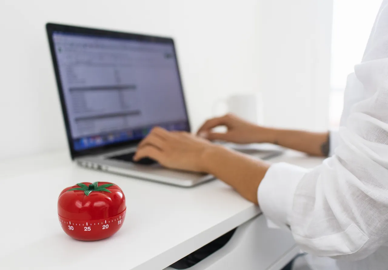 Osoba korzystająca z metody Pomodoro z zegarem i notatkami