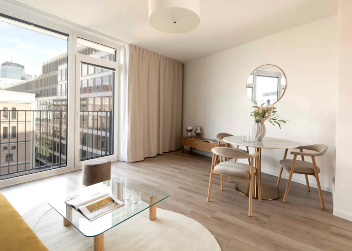 Nowoczesne mieszkanie inwestycyjne co to znaczy? Jasny salon z jadalnią, dużym oknem i widokiem na miasto.