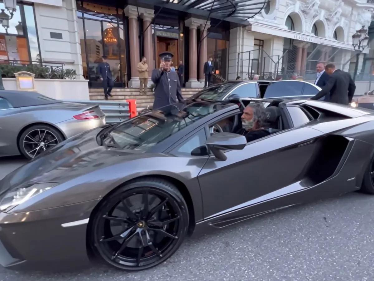 Zeus Lamborghini, kto to? Mężczyzna z siwą brodą w szarym Lamborghini Aventador przed hotelem Le Louis XV.