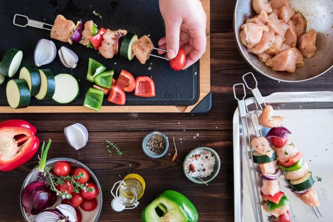 Przygotowanie szaszłyk&oacute;w na grillu: kurczak, cukinia, papryka i cebula na patyczkach.