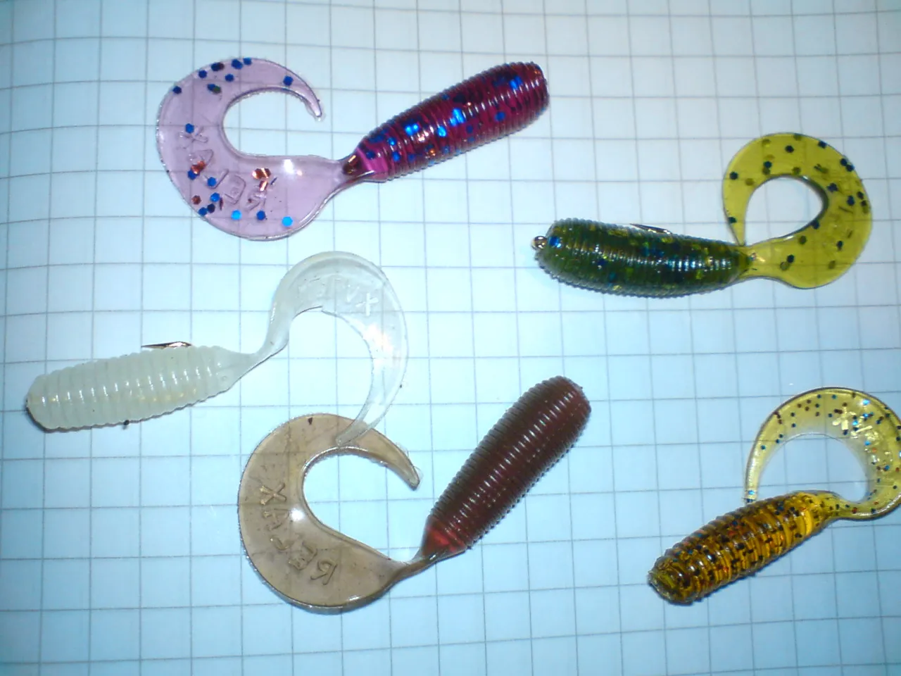 Kolorowe paproszki na okonia, gotowe do akcji. Różowe, zielone, żółte i brązowe, z brokatem i prążkami.