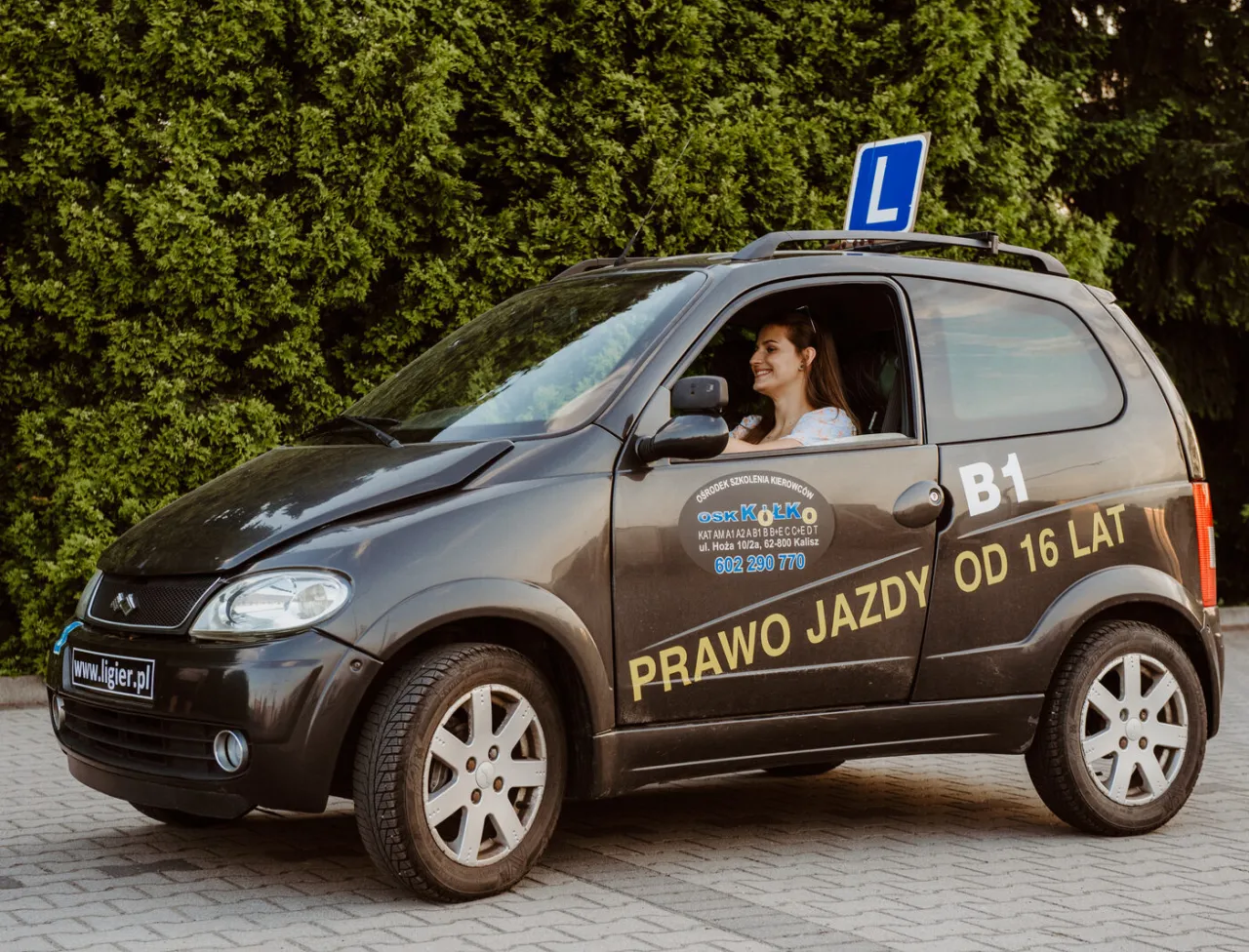 Młoda kobieta za kierownicą pojazdu z literą 