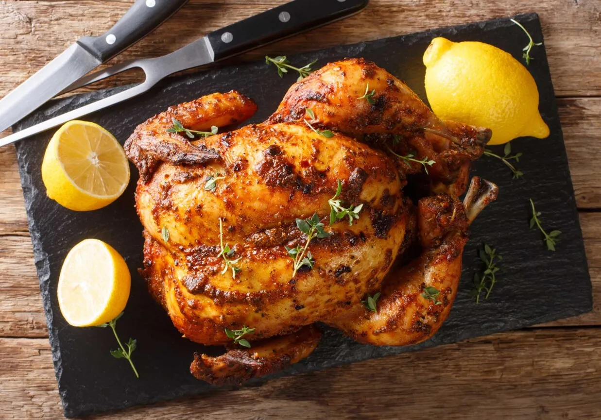Złocisty kurczak pieczony w całości, z cytryną i ziołami, gotowy do podania.