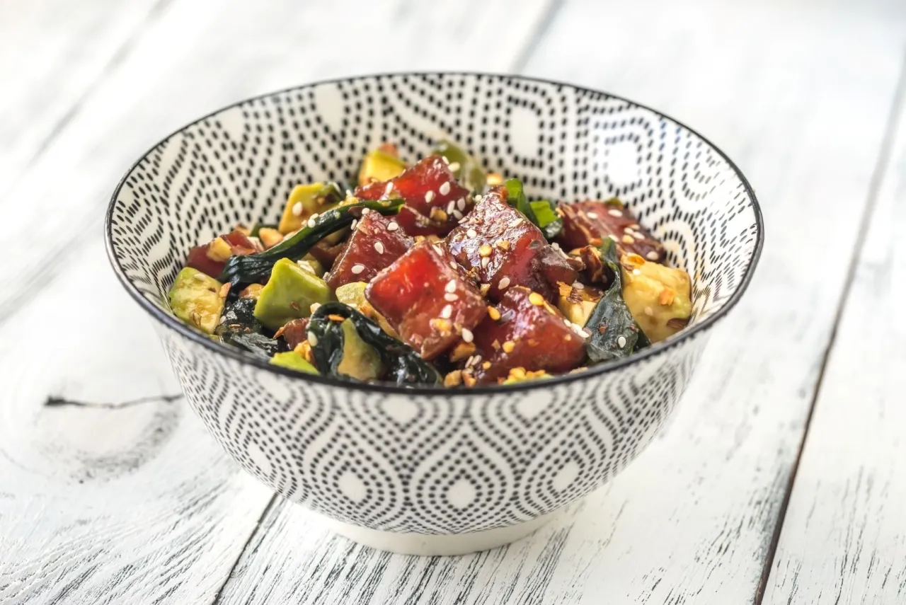 Miseczka z poke bowl: kostki surowej ryby, awokado i ciemnozielone wodorosty wakame. Idealny wakame przepis na lekki posiłek.