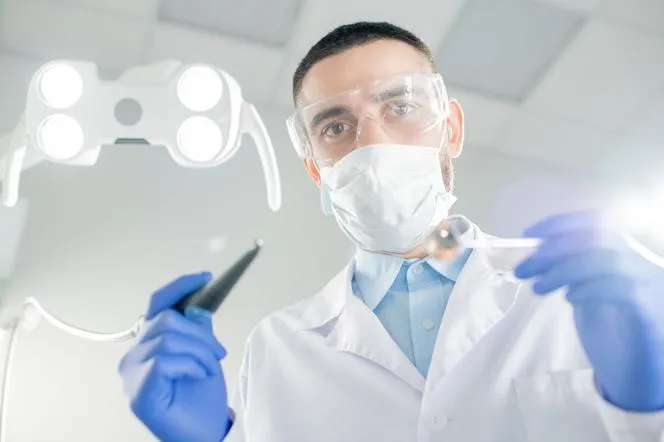 Pacjent w poczekalni u dentysty w maseczce i bez