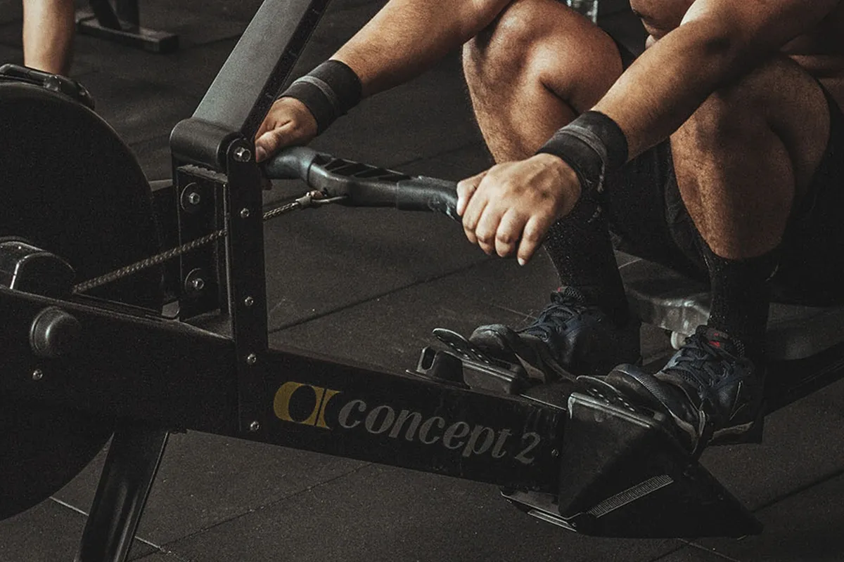 Mężczyzna ćwiczy na wioślarzu Concept 2. Pokazuje, jak prawidłowo używać wioślarza, aby ćwiczyć.
