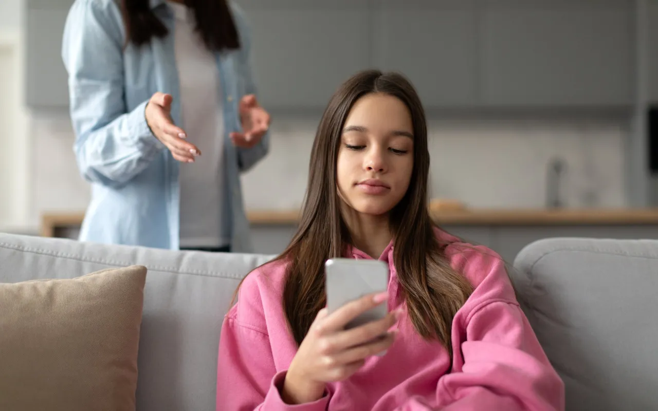 Nastolatek z telefonem w ręku i rodzic obok