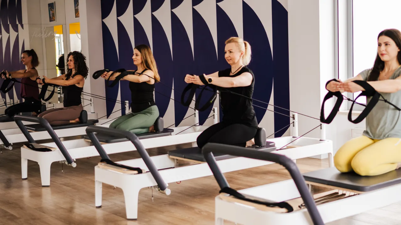 Kobiety ćwiczą pilates na reformerach. Czy pilates odchudza? Regularne ćwiczenia wzmacniają ciało i mogą wspierać proces redukcji wagi.