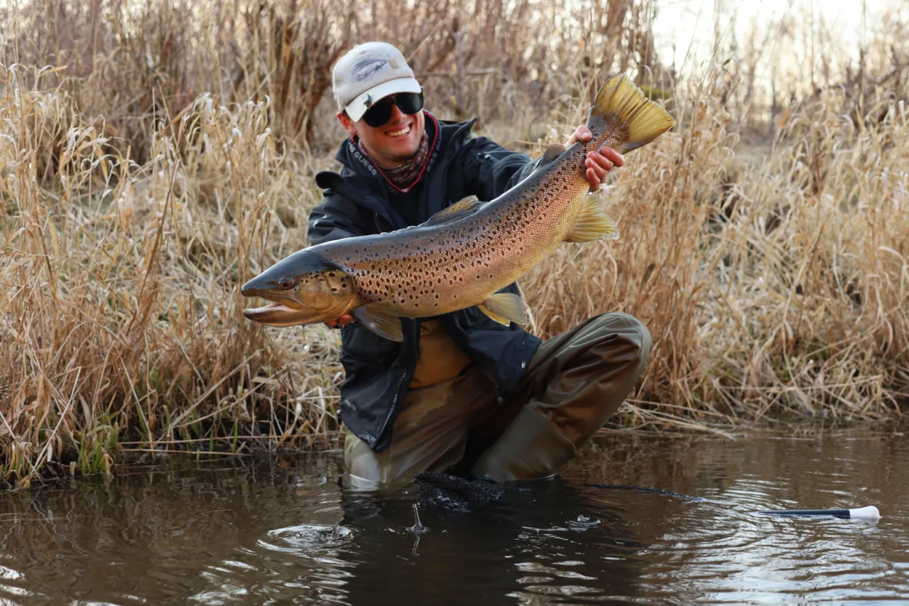Szczęśliwy wędkarz trzyma w rękach okazałego pstrąga. Widać, jaka wędka na pstrąga sprawdziła się najlepiej.